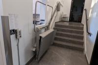 Lift opening one safety arm to allow exit at top of stairs